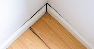 Warped wooden floor and baseboard showing signs of hidden water leak damage