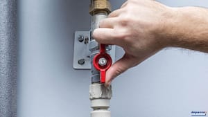 Hand turning main water shut off valve to stop plumbing leak