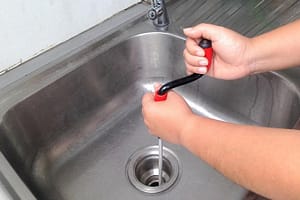 Using drain snake to unclog kitchen sink drain pipe