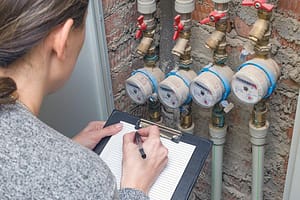 Professional Leak Detection Techniques showing a homeowner checking a residential water meter for hidden water leaks